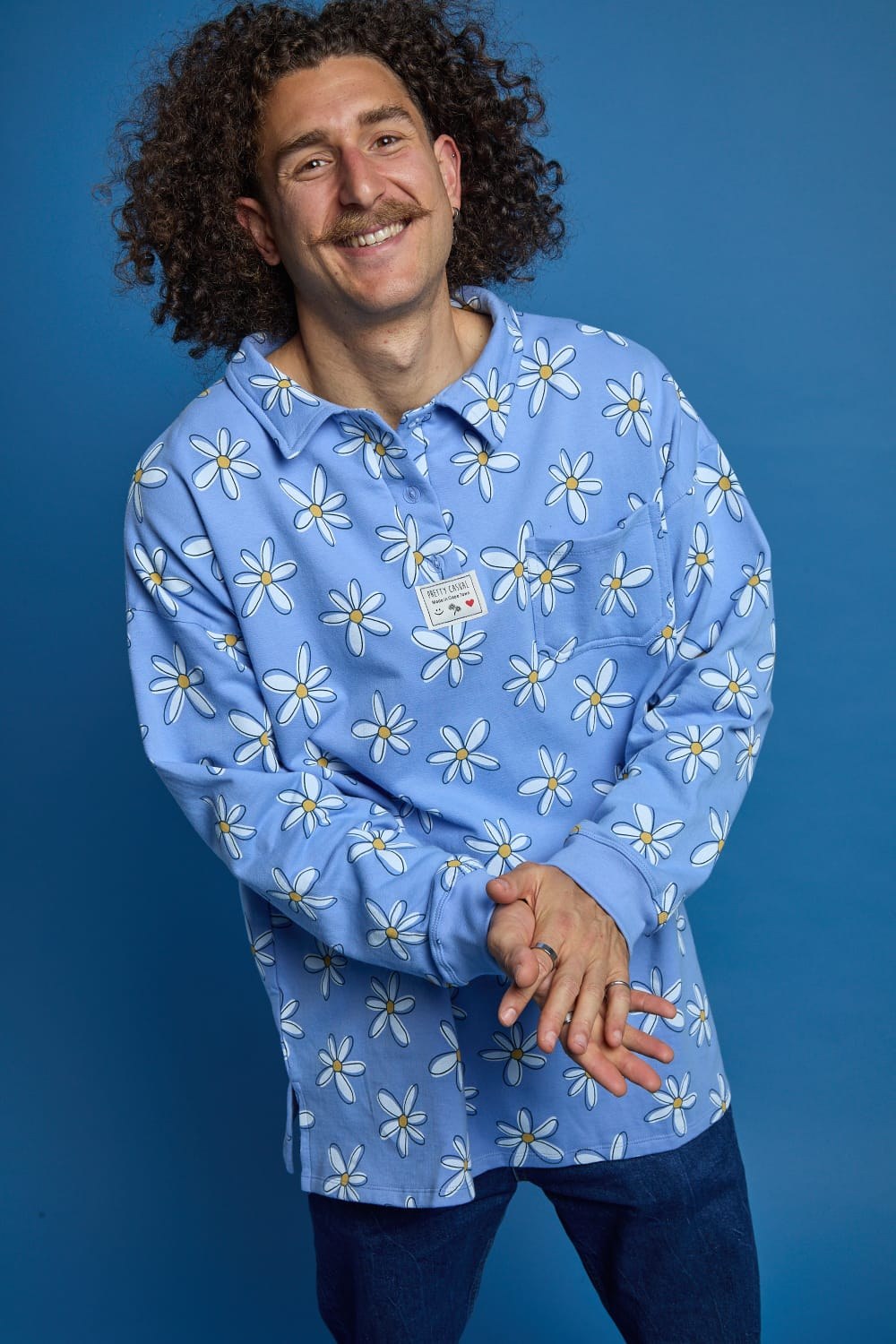 Seth Jacobs smiling in a blue daisy-print shirt against a blue background